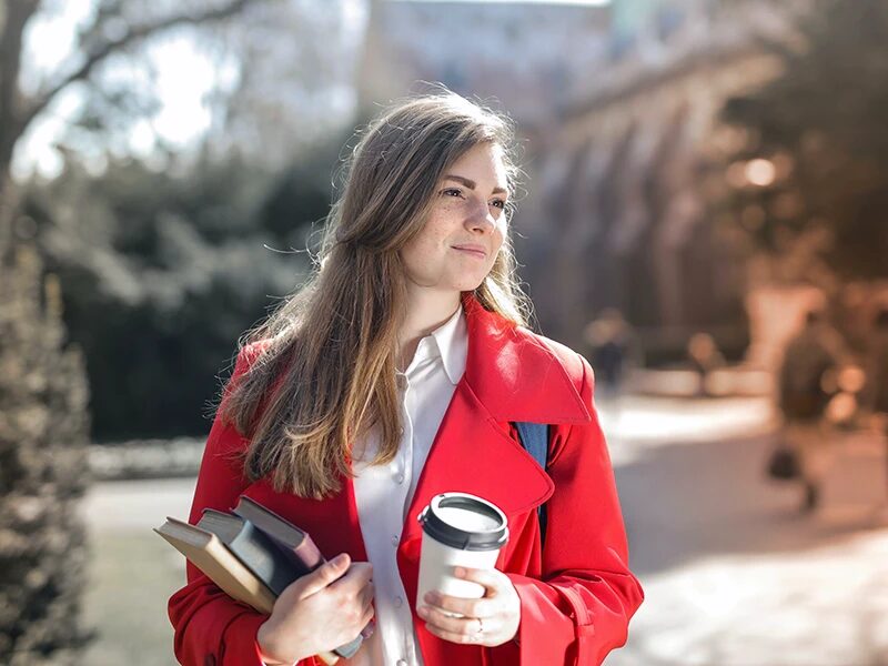 студентка з книгами та чашкою кави